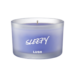 Sleepy scented candle, candle is shown from the side, where the purple wax can be seen through frosted glass.