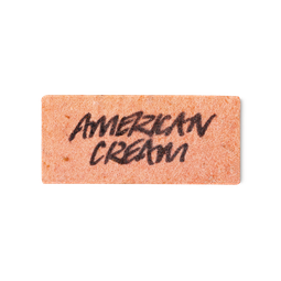 A peachy pink, rectangular washcard, consisting of apple pulp, with 'American Cream' written across it in black Lush writing.