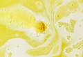 The bath bomb giving off lots of yellow bubbles and fizz, while floating in a creamy mix of white foam and yellow water.