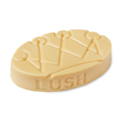 Lord of Misrule. A cream oval shaped, solid massage bar, with a crown design on top, and the Lush logo moulded along the edge.