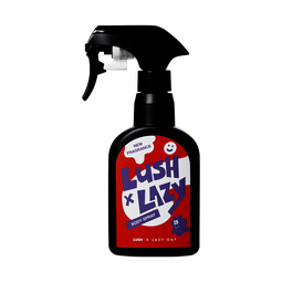A spray bottle containing Lush x Lazy body spray, made of opaque black Lush plastic with a red, white and purple lable.