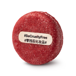 New. A bright red, circular solid shampoo bar, topped by a wooden stick with #BeCrueltyFree written across it.