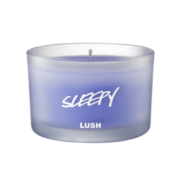 Sleepy scented candle, candle is shown from the side, where the purple wax can be seen through frosted glass.