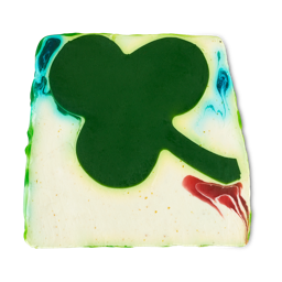 Alban Eilir. A thick, off-white soap slice showing a large, green, clover-shape in the centre with subtle, smalls swirls of red and blue around. 