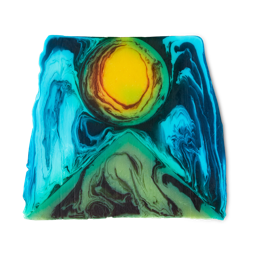 Alban Hefin is a thick, off-square slice of soap. An abstract design shows a green, pyramid-like shape at the bottom with a bright yellow, sun-like circle, surrounded by blue swirls. 
