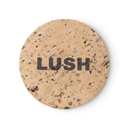 Cork Pot. A round, beige, product holder made of natural cork. LUSH is printed on top, in black, bold letters.