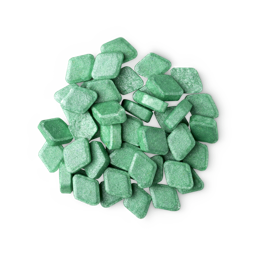 A pile of small, diamond-shaped, green Crème De Menthe mouthwash tabs shot from above.