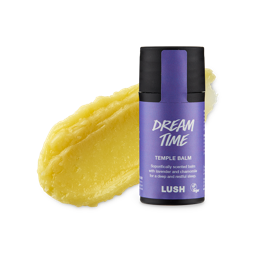 Dream Time. A smudged swatch of thick, natural yellow balm. In front of it stands the cylindrical black packaged Temple Balm with a purple product sticker. 