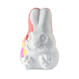 Follow The White Rabbit. A white bath bomb shaped like a sitting rabbit with ears pointed up and pink and yellow just peeking at the edge.