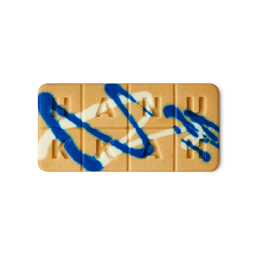 Gelt Melt. An oblong, honey-coloured wax melt with blue and white splats is sectioned into 8 squares spelling "LUSH MELT".
