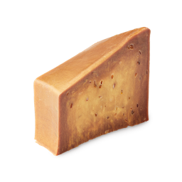 Golden Linseed. A cake-slice-shaped soap block coloured like golden caramel scattered with linseeds.