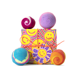 Happy Daze. A square box, printed with a yellow, pink and purple smiley face design, tied with orange cord and a gift tag.