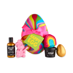 Happy Egg. A large, colourful gift box shaped like an egg, wrapped in pink ribbon. In front are five Easter-themed bath and shower products. 
