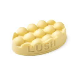 Hottie. A buttery yellow, oval shaped, solid massage bar, with LUSH imprinted on its edge, and a bumpty textured top surface. 