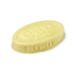 Joints. A buttery yellow, oval shaped, solid massage bar, with LUSH imprinted on its edge, and CBD 25mg embossed on top.