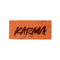 An orange, rectangular washcard, consisting of apple pulp, with 'Karma' written across it in black Lush writing.