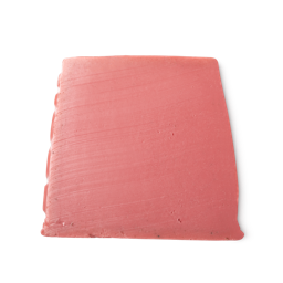Lotus Flower. A rosy pink, smooth, trapezium shaped soap, with bumps along its left side, and tiny brown flecks at its base.
