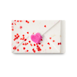 Love Letter. A bath bomb shaped like an envelope. It is white with small red hearts sprinkled throughout and a pink heart seal.