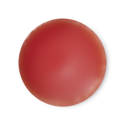 An arial view of orangey, bright red, balm-like Lust solid perfume.