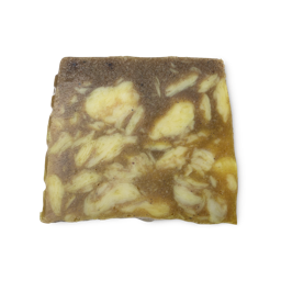 Sandstone. A sandy yellow coloured, trapezium shaped soap, with a roughly textured surface and bumps along its left side.