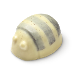 Scrubee solid body butter. The image shows a pale cream, bee-shaped product with a rounded top and small antennae. It features two dark grey, textured stripes across its back, appearing smooth and solid.