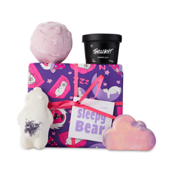 Sleepy Bear. A purple, wrapped gift box surrounded by 4 lavender LUSH products. 