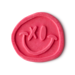 Bubble Dance bubble bar. A vibrant, pink bubble bar shaped like a classic smiley face with a graffiti “X” for one of the eyes.