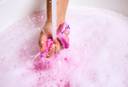 Image shows model crushing the moulded Snow Fairy Fun product under running water with pink bubbles below.