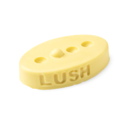 Therapy. A buttery yellow, oval shaped, solid massage bar, with a design of 3 small holes cut out with 1 bump in a line.
