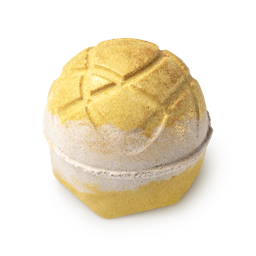 Turmeric latte. A yellow and gold round bath bomb with hatching on top and a cream-coloured stripe down the middle