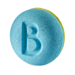 Two Families. An almost macaroon-shaped bath bomb stood at an angle. The top half is a textured blue with a large letter "B" embossed on top. The Bottom half is a contrasting bright yellow. 