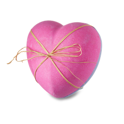 Flower Bombshell. A large, heart-shaped bath bomb made of two halves, one pink and one purple, tied together in a bow.
