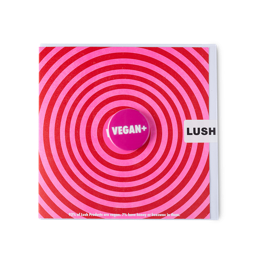 Vegan +. A square greetings card with a large, vibrant, red and pink swirl with a detachable badge printed with "VEGAN +"